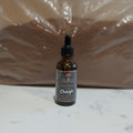 A bottle of Chaga extract tincture with a black dropper cap, placed next to a clear plastic bag containing ground chaga powder.